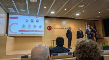 The Cambra de Comerç de Sabadell auditorium during the Impulsa Startup Demo Day 2025, featuring a presentation screen with judges' profiles and speakers on stage addressing the audience.